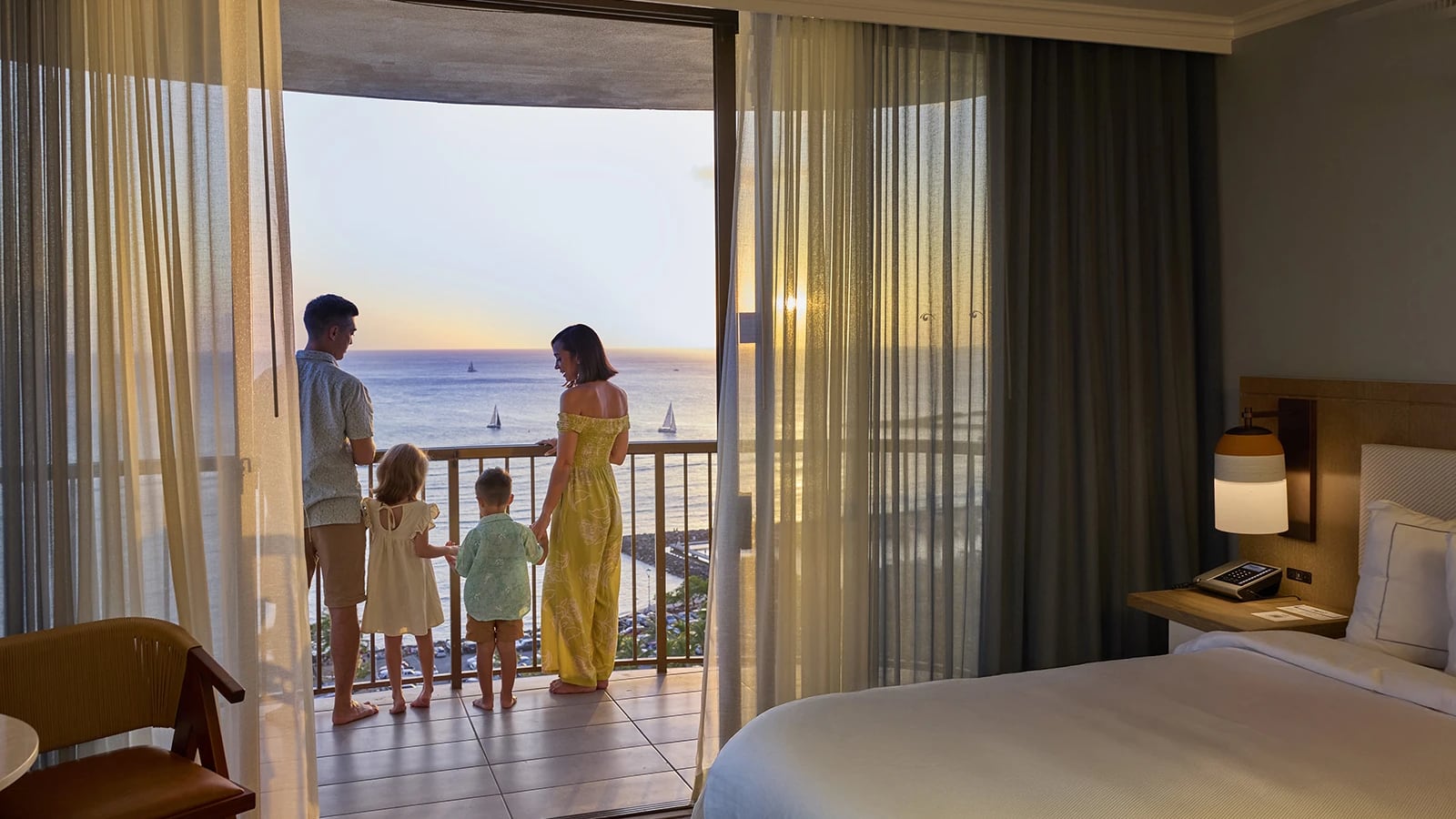 Family standing on a balcony at a Hilton residence overlooking a body of water
