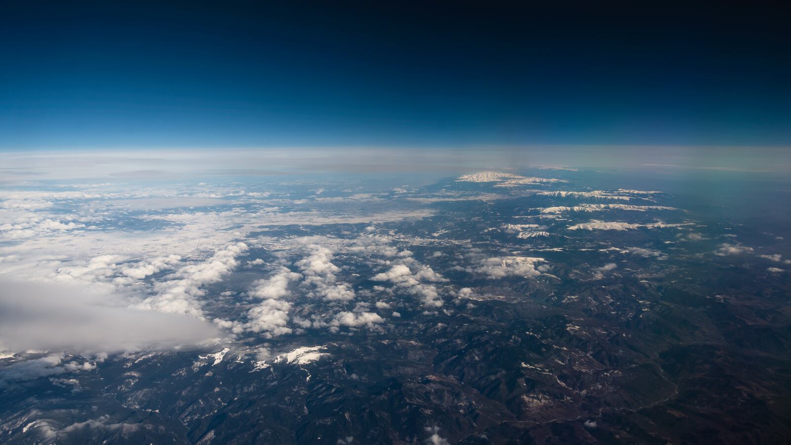 Panorama view from the airplane window to mountains clouds and blue sky