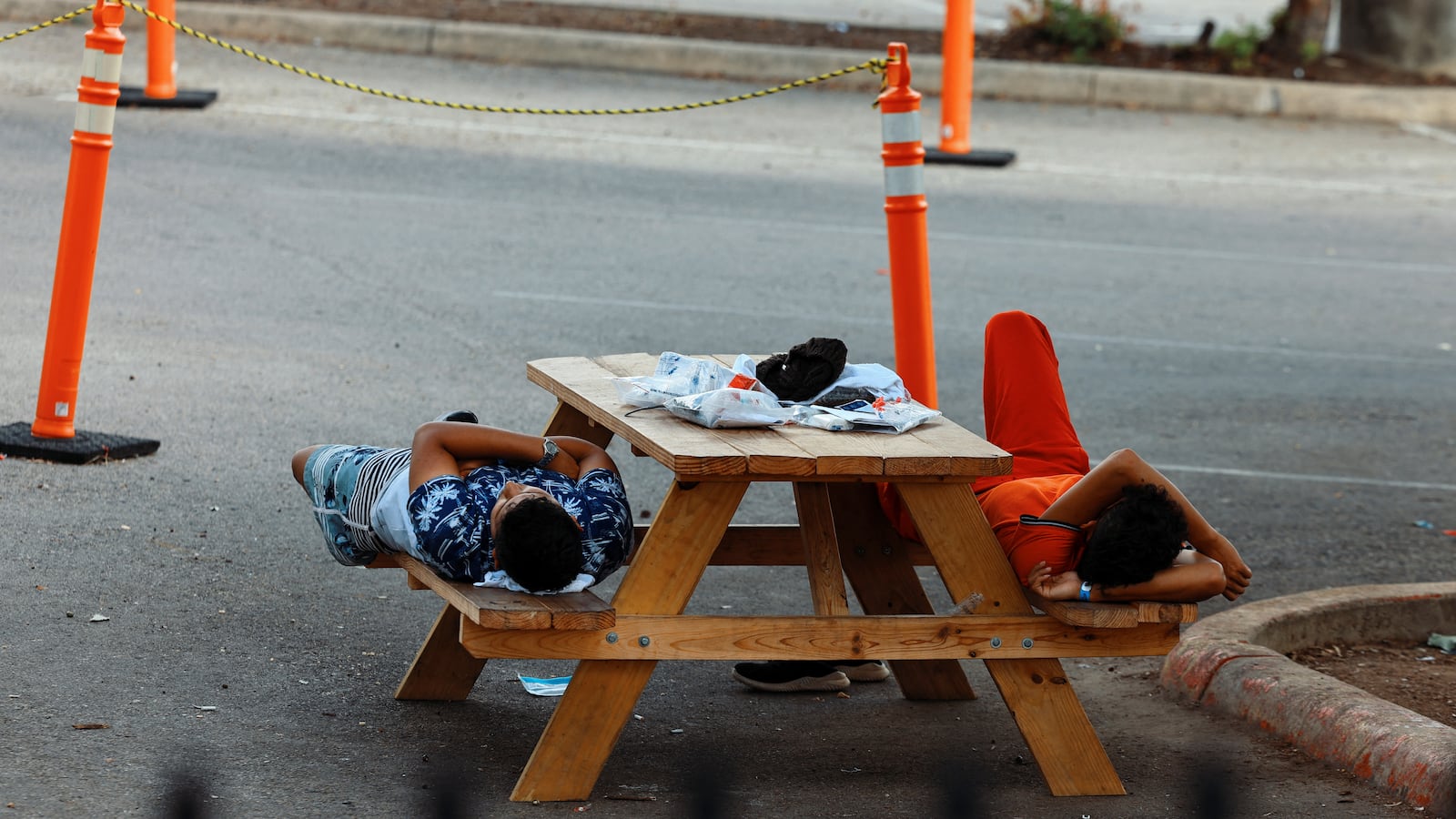 A photo of migrants laying on a bench outside the City of San Antonio Migrant Resource Center.