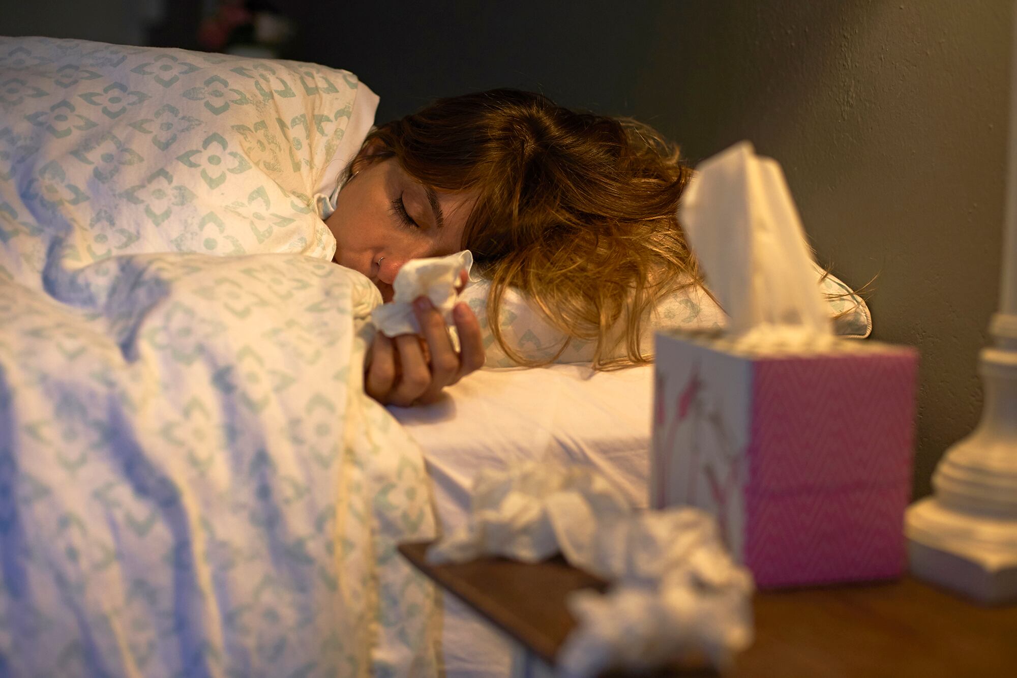 Sick woman using tissues in the bed