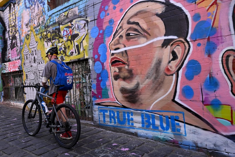 A man passes a mural by Jarrod Grech of Ahmed al Ahmed