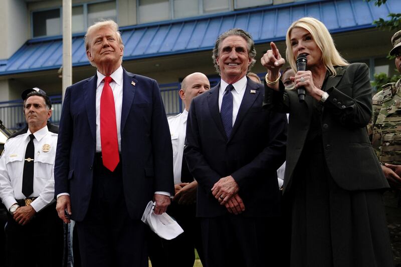 U.S. Attorney General Pam Bondi speaks as U.S. President Donald Trump listens, while he attends U.S. Park Police Anacostia Operations Facility to meet with police and the military, after deploying National Guard troops in the nation's capital, in Washington, D.C., U.S., August 21, 2025.  REUTERS/Nathan Howard