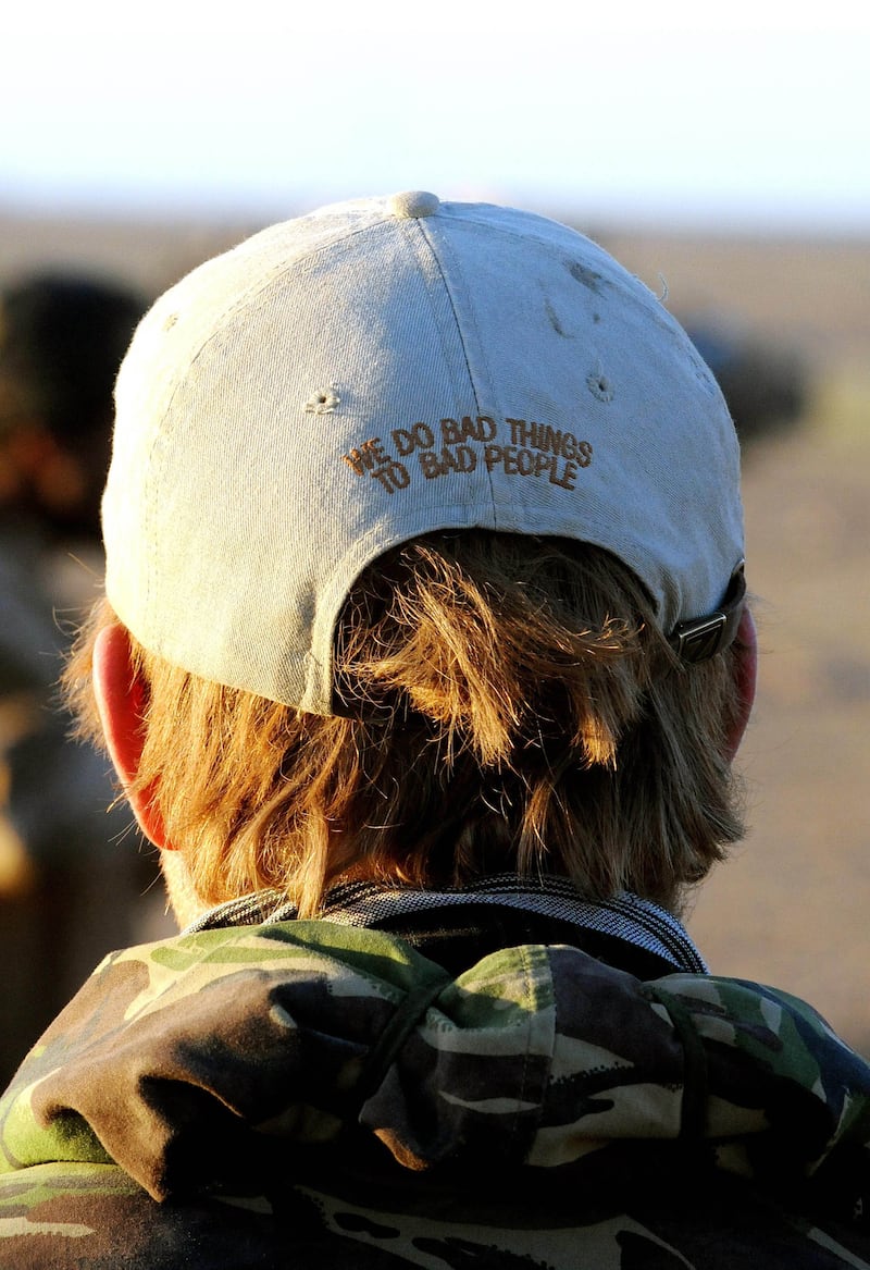 Prince Harry wears a baseball cap with the message 'We do bad things to bad people' in the desert on February 19, 2008 in Helmand Province, Afghanistan.