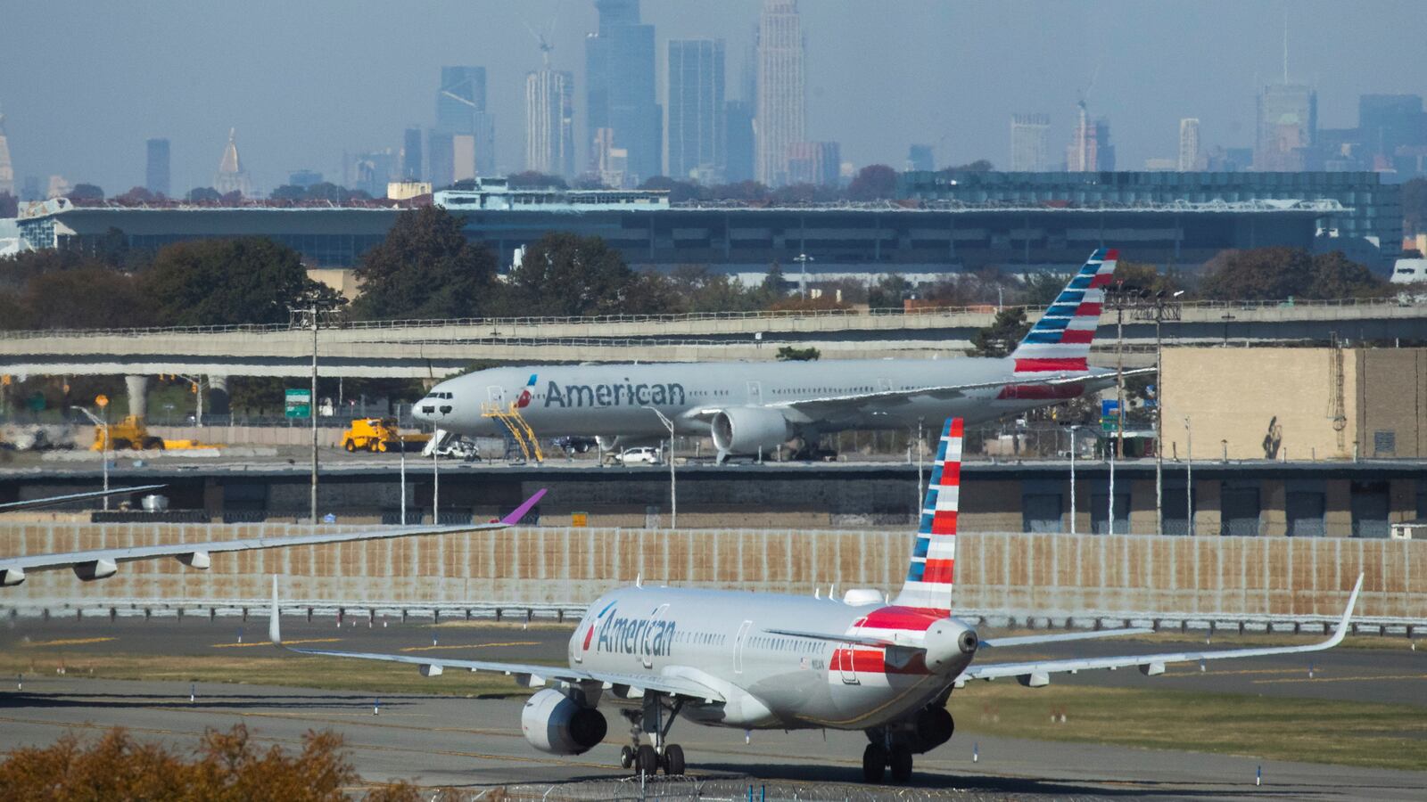 American Airlines planes taxi on the tarmac as the skyline of New York City is seen in the background from the JFK International Airport in New York, U.S., November 8, 2021.