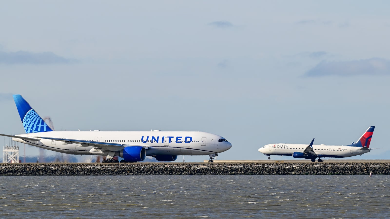 SAN FRANCISCO, CALIFORNIA - JULY 24: A Delta Airlines plane lands as a United Airlines plane is taxiing to takeoff at San Francisco International Airport (SFO) in San Francisco, California, United States on July 24, 2025.