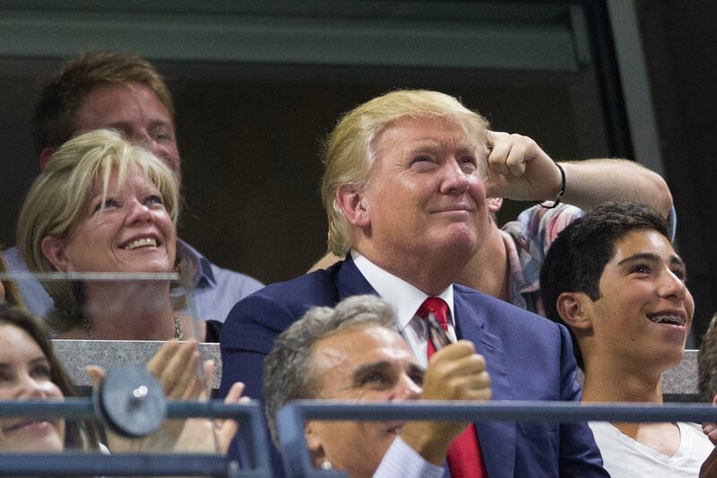 U.S. Republican presidential candidate Donald Trump (C) watches as Serena Williams of the U.S. plays against her sister and compatriot Venus Williams in their quarterfinals match at the U.S. Open Championships tennis tournament in New York, September 8, 2015.  REUTERS/Carlo Allegri