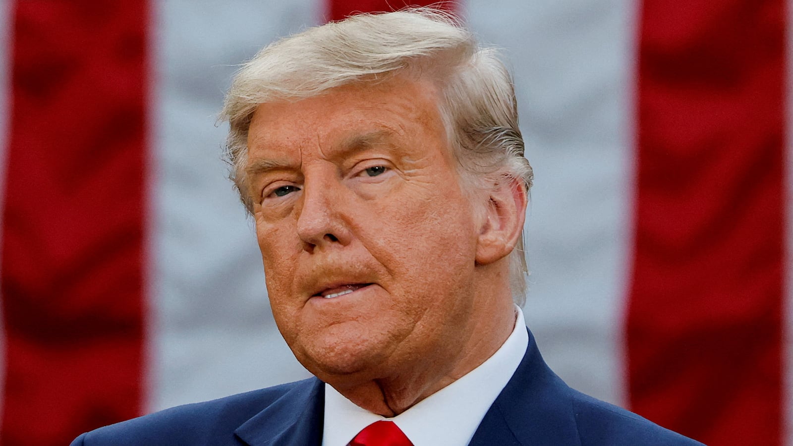 Donald Trump stands in front of a U.S. flag