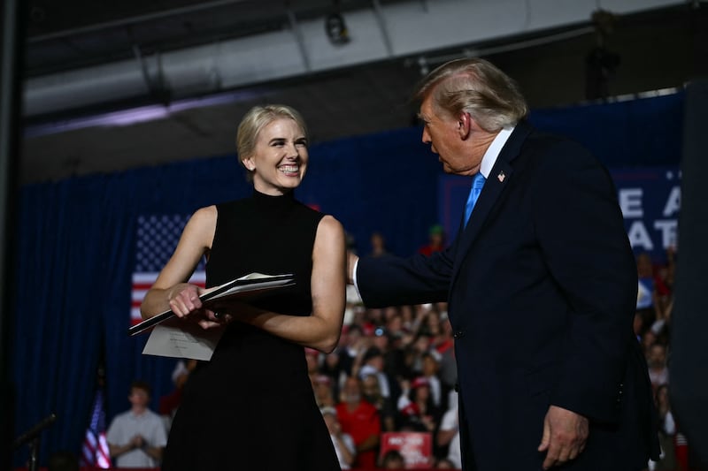 Executive assistant to President Donald Trump, Natalie Harp, stands next to President Donald Trump as he holds up an executive order during a campaign rally at Pinnacle Bank Expo Center in Grand Island, Nebraska, on October 5, 2026.