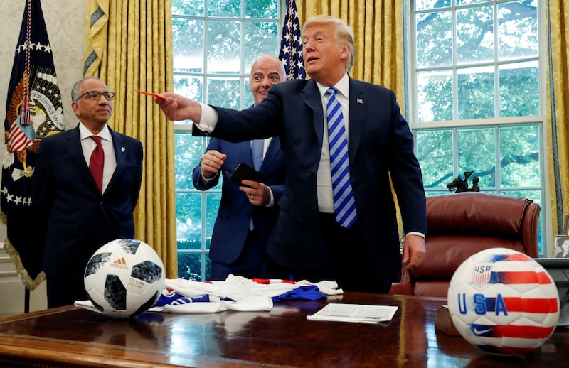 U.S. President Donald Trump pretends to throw a red card at the news media given to him by the President of FIFA Gianni Infantino, center, as Carlos Cordeiro, President of the US Soccer Federation, stands nearby in the Oval Office at the White House in Washington, D.C., U.S. August 28, 2018.
