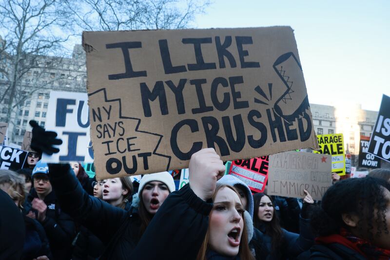 A woman holds a sign in a crowd that says "I like my ICE crushed. NY says ICE Out"