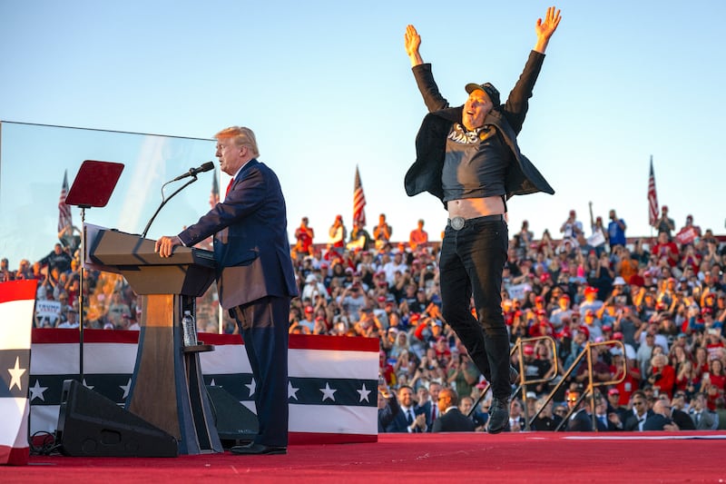 Tesla CEO Elon Musk (R) jumps on stage as he joins Donald Trump during a campaign rally at site of his first assassination attempt in Butler, Pennsylvania on October 5, 2024.