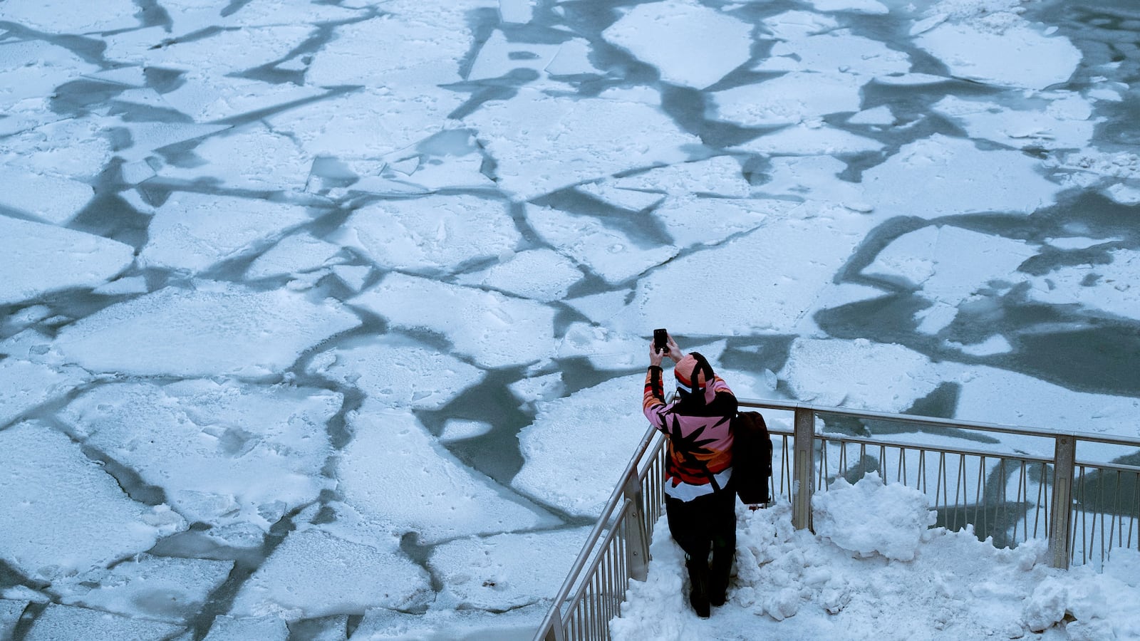 pedestrian stopping by chicago river to take picture of ice polar vortex frost quake frostquake steven battaglia climate change