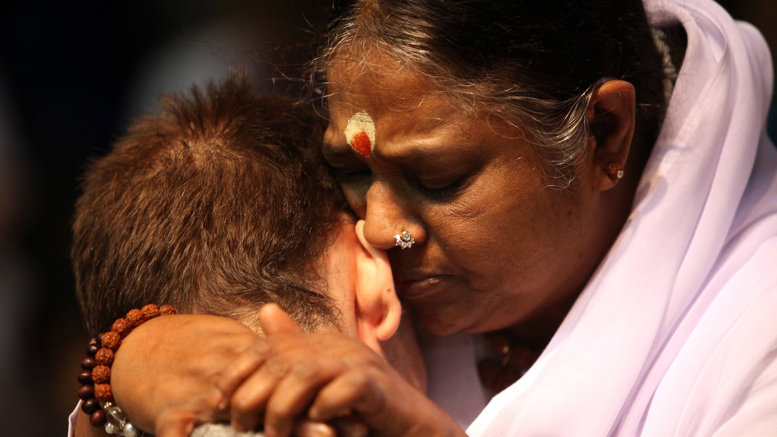 articles/2014/07/20/patted-down-by-india-s-hugging-saint/140718-genis-hug-tease_cvkx68