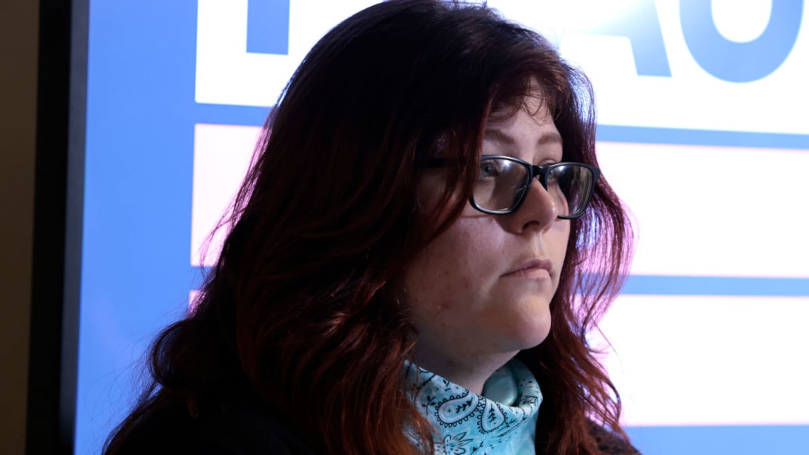 Lauren Handy, wearing a blue bandana around her neck, stares forward blankly.