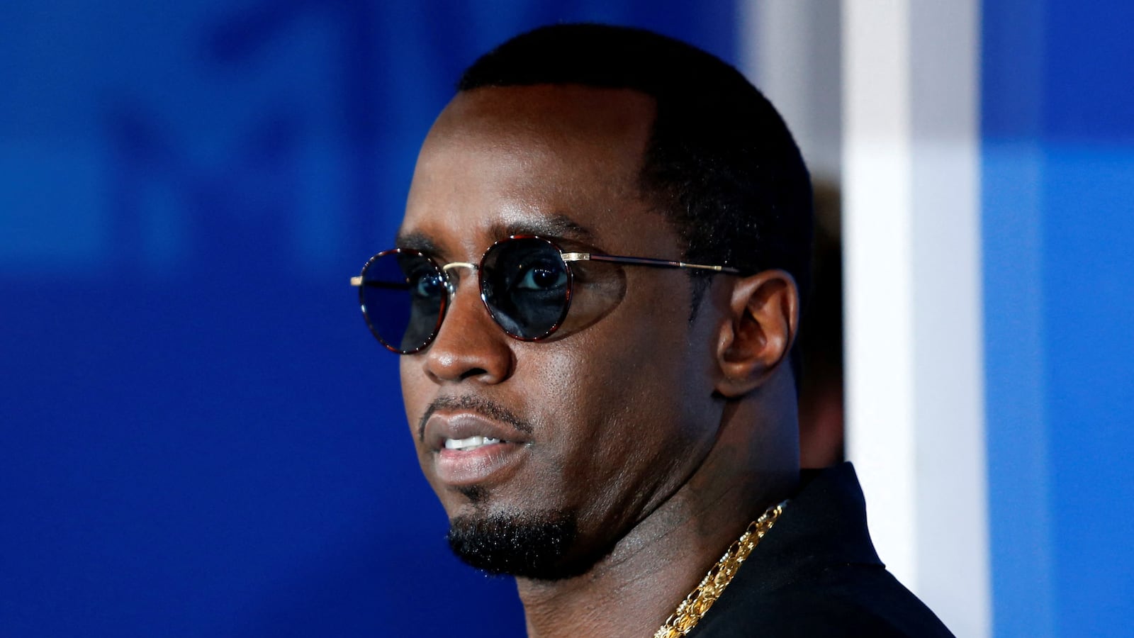 Sean Combs, wearing glasses, stares to his side.