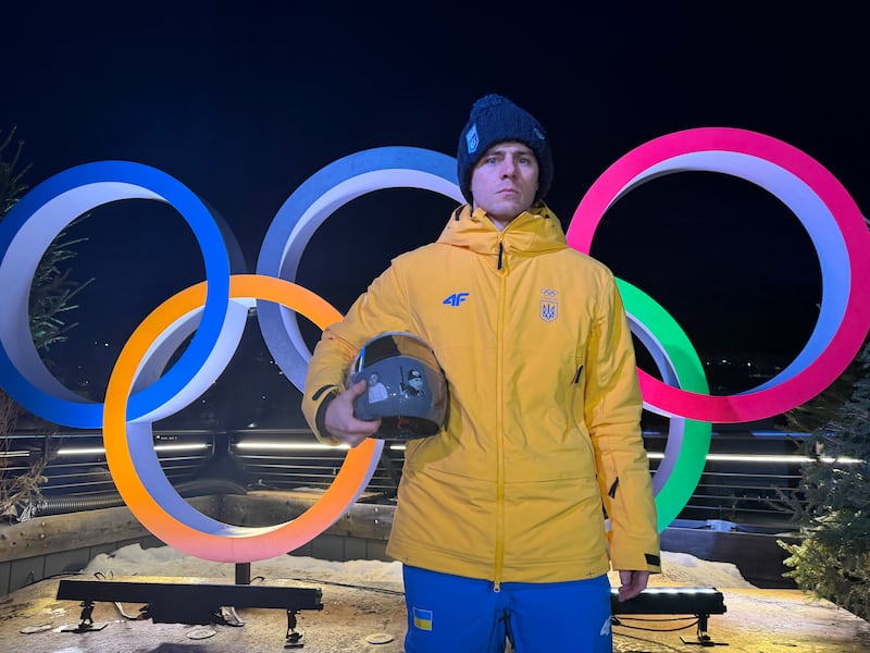 TOPSHOT - Vladyslav Heraskevych of Ukraine poses with his helmet that serves as a tribute to athletes who have died amid Russia's attack on Ukraine during a press conference in Cortina d'Ampezzo as part of Milano Cortina 2026 Olympic Games, on February 10, 2026. Ukrainian skeleton racer Vladyslav Heraskevych vowed that he would wear his helmet "on race day" despite a ban imposed by Olympic chiefs. (Photo by Andrea BERNARDI / AFP via Getty Images)