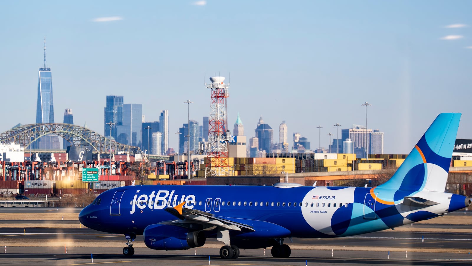 NEWARK, NJ - JANUARY 15: An Airbus A320 plane, operated by JetBlue Airlines at Newark Liberty International Airport (EWK) in front of the skyline of lower Manhattan and One World Trade Center in New York City on January 15, 2026 in Newark, New Jersey. (Photo by Al Drago/Getty Images)