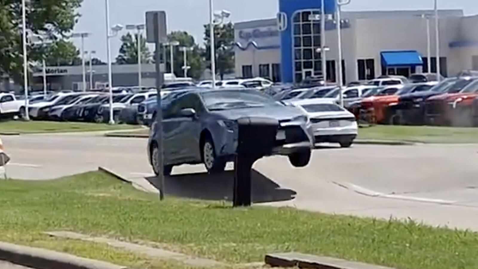 A blue car sails into the air after the ground buckles amid elevated temperatures.