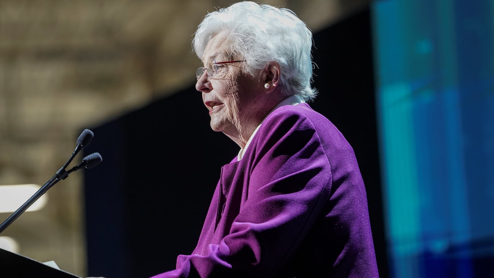 Kay Ivey speaks into a microphone at a podium.