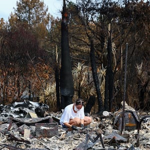 A woman inspects the debris of her parents' home after it was destroyed by a wildfire in Le Porge, Gironde department, France, August 3, 2026, as authorities authorized evacuees to return to the area.