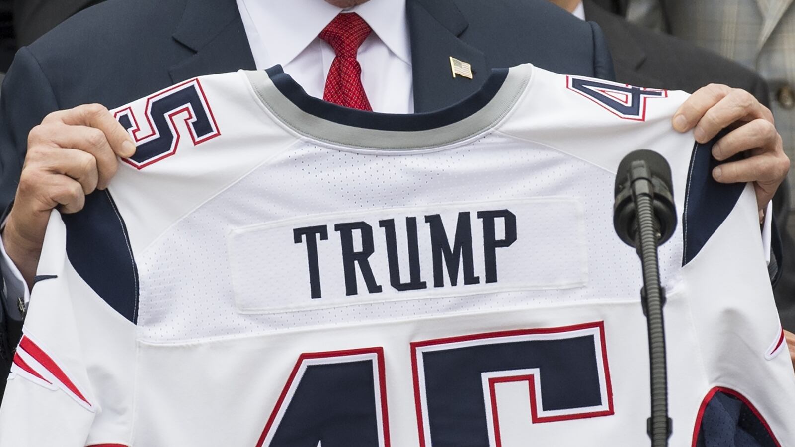 US President Donald Trump holds a jersey given to him by the New England Patriots alongside members of the team during a ceremony honoring them as 2017 Super Bowl Champions on the South Lawn of the White House in Washington, DC, April 19, 2017. / AFP PHOTO / SAUL LOEB (Photo credit should read SAUL LOEB/AFP via Getty Images)