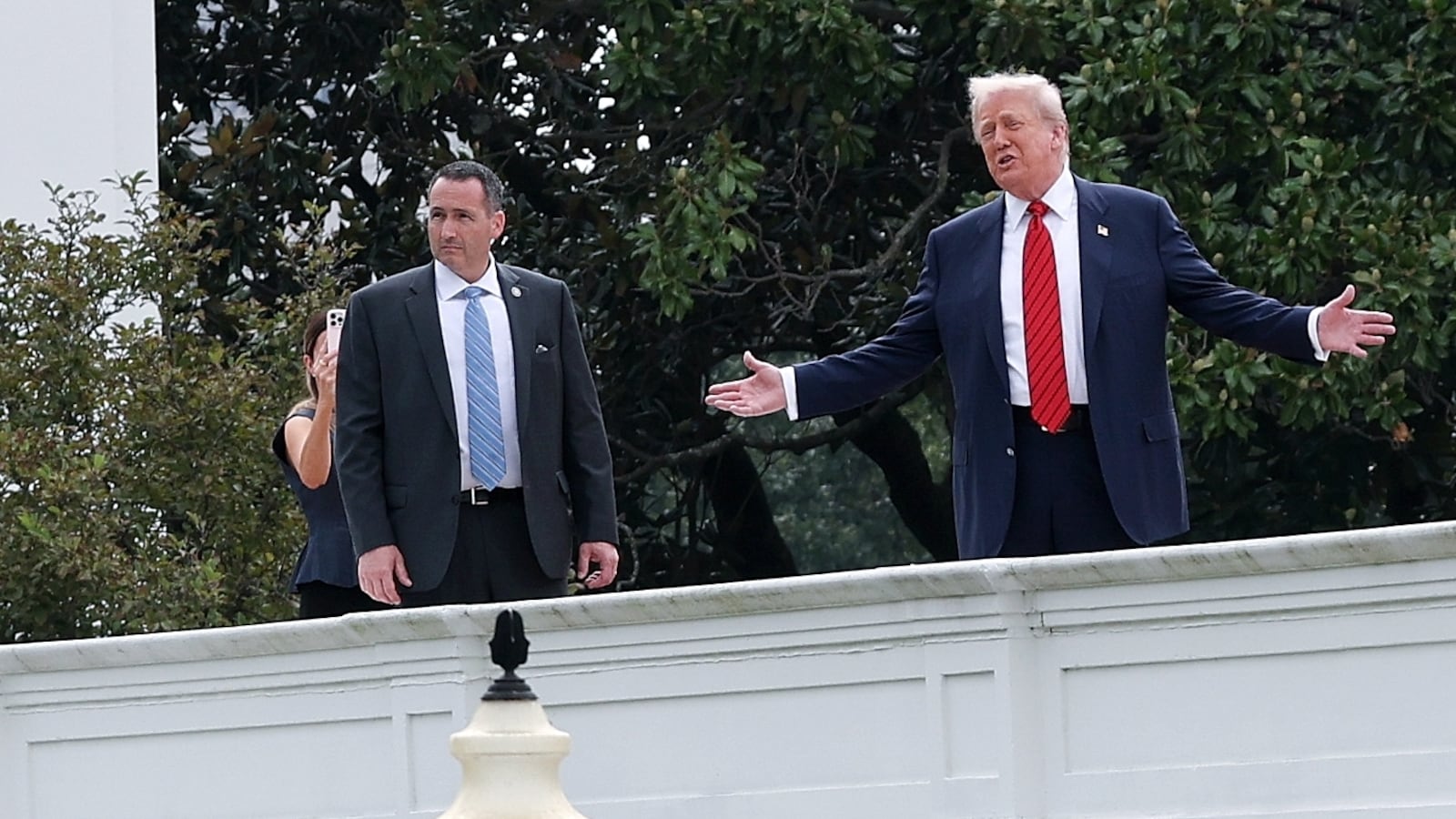 U.S. President Donald Trump gestures while answering questions from reporters as he tours the roof of the West Wing of the White House