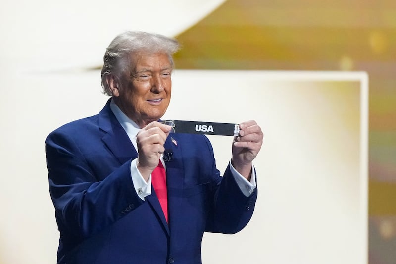 President Donald Trump shows the card reading USA during the draw for the 2026 FIFA Football World Cup taking place in the US, Canada and Mexico, at the Kennedy Center, in Washington, DC, on December 5, 2025.