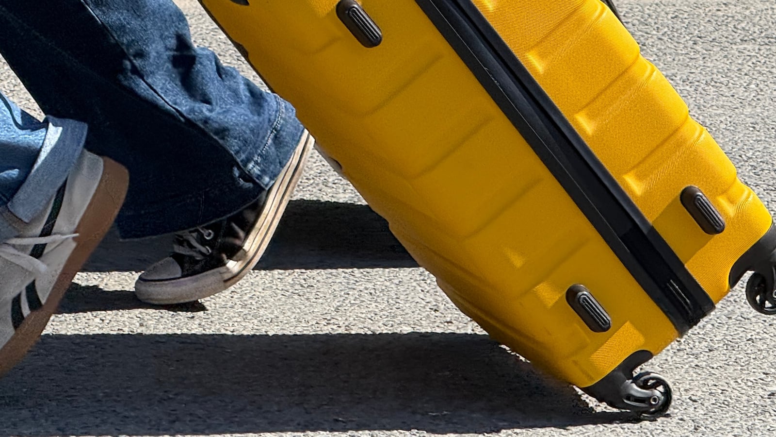 08 August 2025, France, Paris: Two young people pull trolley suitcases through a street in Paris not far from Notre-Dame Cathedral.