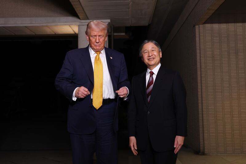 U.S. President Donald Trump adjusts his blazer as he is greeted by Japanese Emperor Naruhito