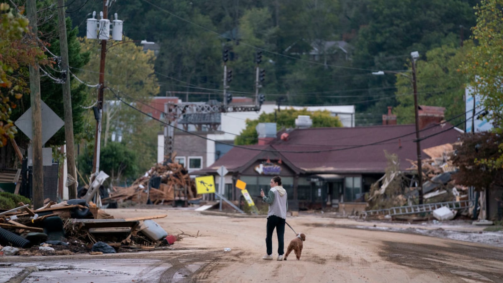 A woman walks her dog on a destroyed street in Asheville, North Carolina.