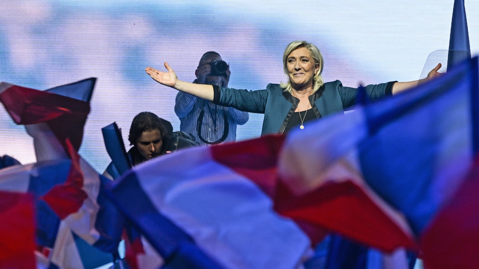 Marine Le Pen gestures to a crowd waving French flags