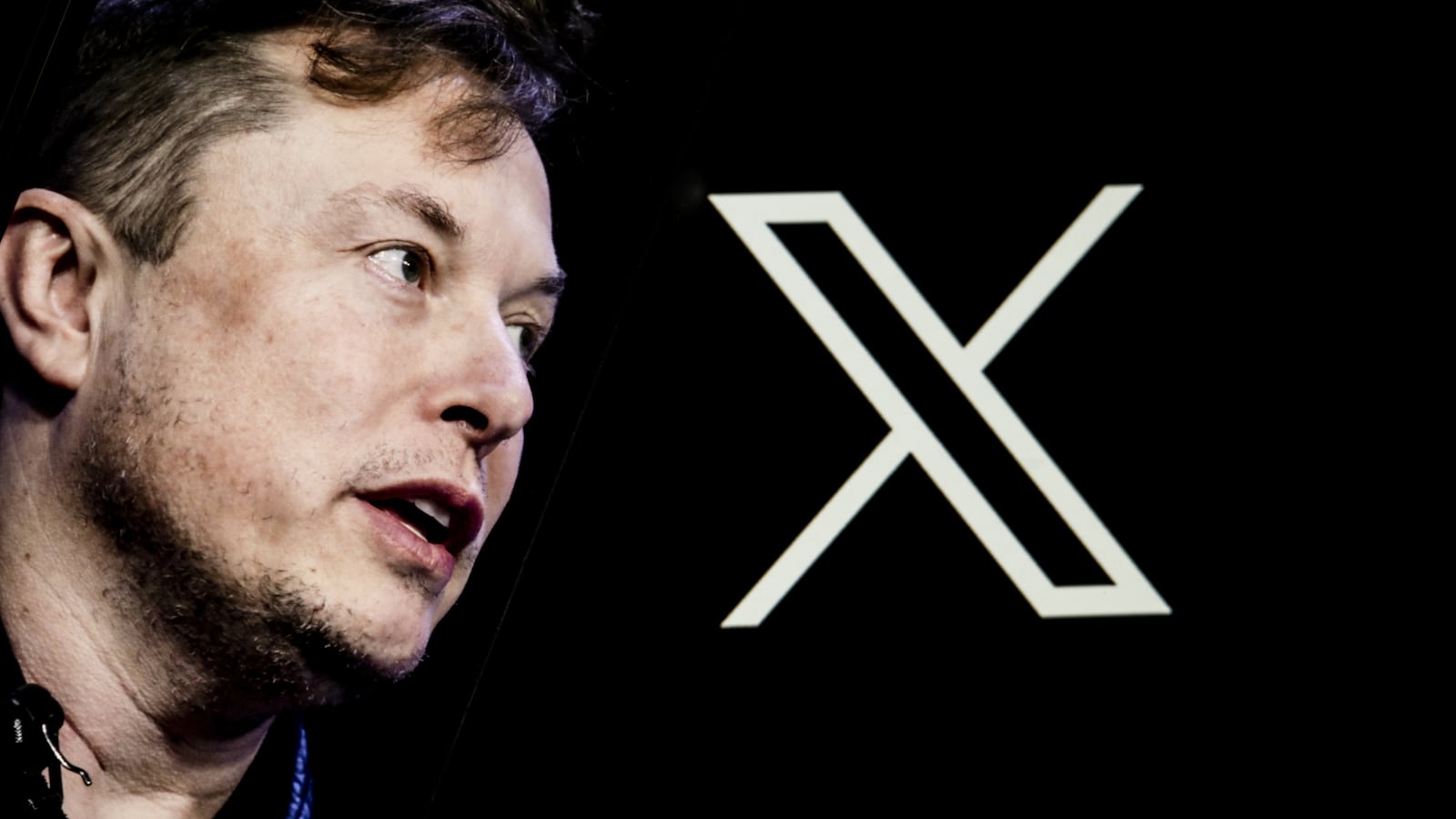 Elon Musk's photo is displayed on a phone screen in front of a computer screen displaying the new logo of 'Twitter' i