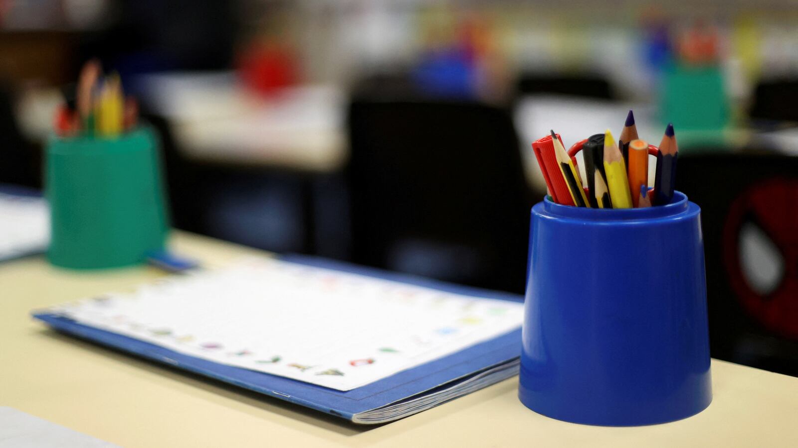 A teacher's desk with a cup of pencils