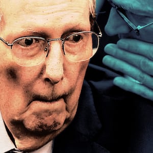 An aide whispers in Mitch McConnell's ear