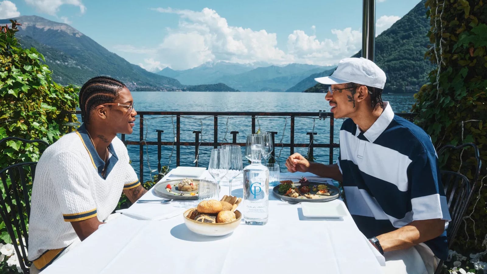 Two mean wearing boohooMAN clothing having a meal together in a scenic outdoor setting
