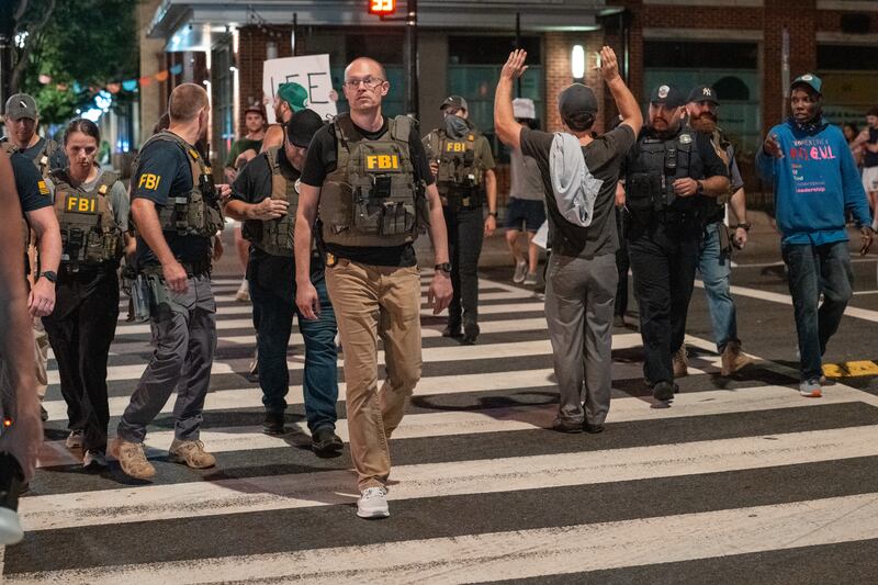 WASHINGTON, DC - AUGUST 13: FBI agents are followed by protesters in the U street neighborhood on August 13, 2025 in Washington, DC. U.S. President Donald Trump announced plans to deploy federal officers and the National Guard to the District in order to place the DC Metropolitan Police Department under federal control and assist in crime prevention in the nation's capital.  (Photo by Andrew Leyden/Getty Images)