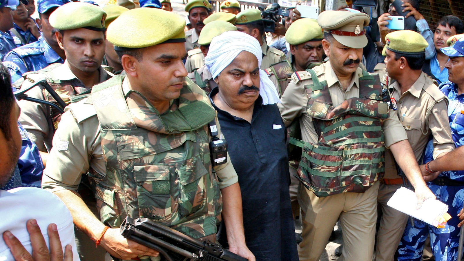 Police officers escort Atiq Ahmed outside a court in Prayagraj.