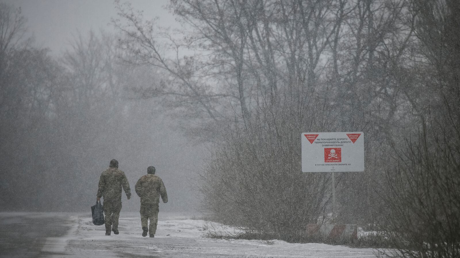 Ukrainian border guards walk past a mine-warning sign near the contact line between pro-Russian rebels and Ukrainian troops in Mayorsk, Ukraine, February 25, 2019.