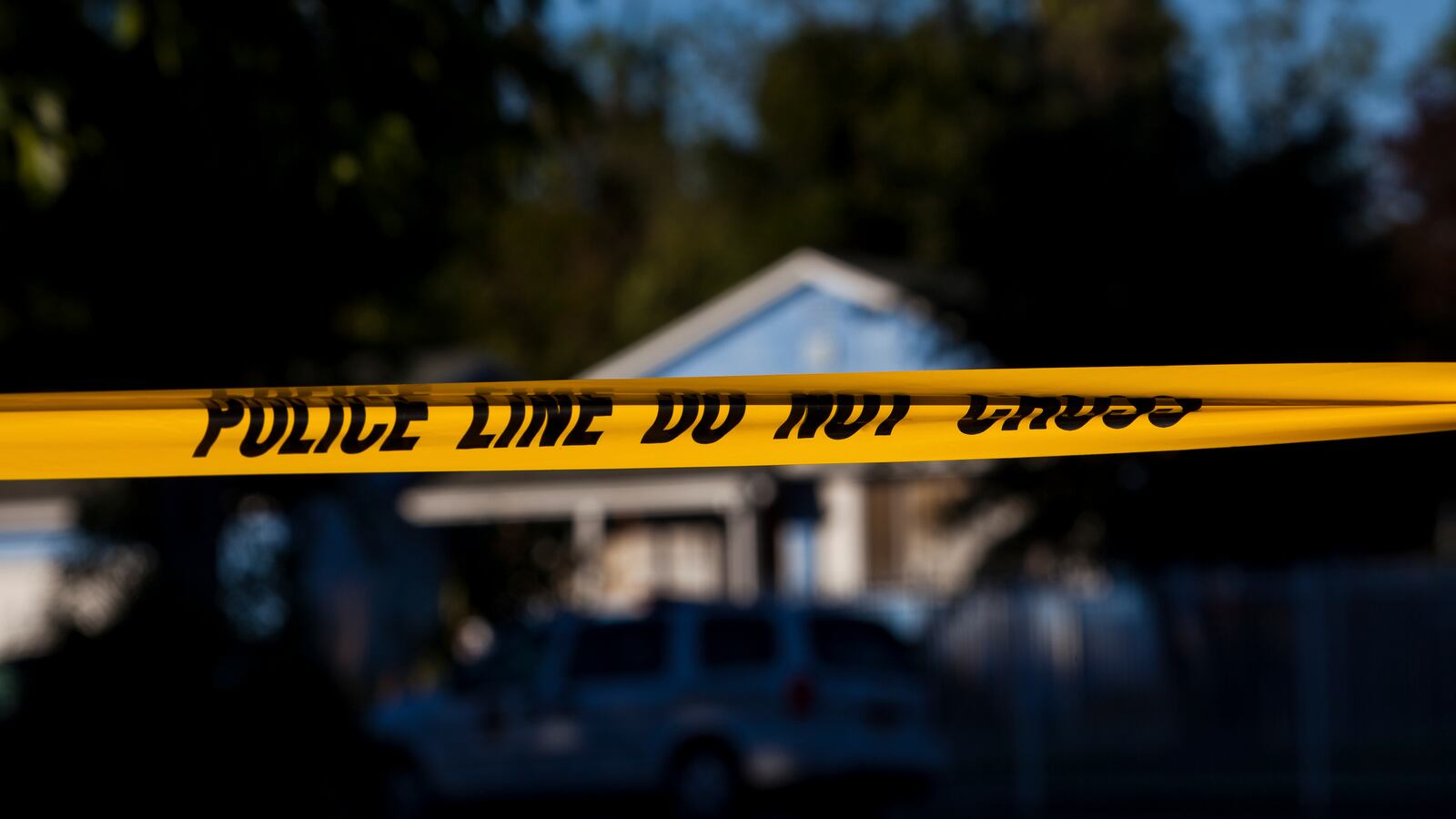 Yellow police tape is put in front of a blue home.