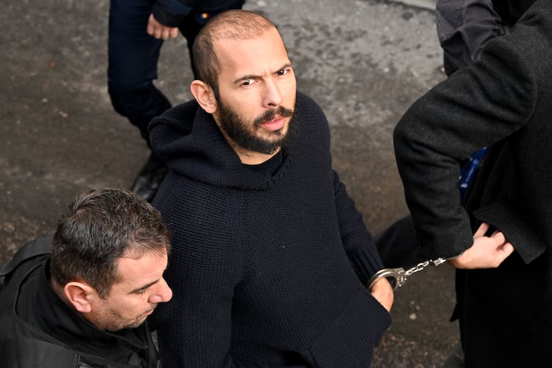 British-US influencer Andrew Tate arrives handcuffed and escorted by police at a courthouse in Bucharest on February 1, 2023.