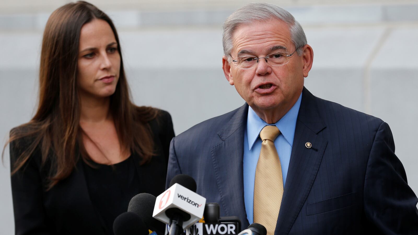 Senator Bob Menendez speaks to journalists after arriving to face trial for federal corruption charges as his daughter Alicia Menendez looks on outside.