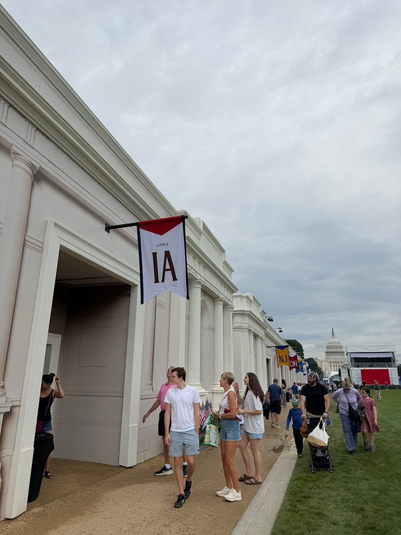 A handful of people walk past the Iowa booth at the Great American State Fair.