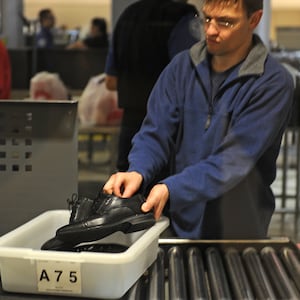 An air traveler places his shoes in a bin before passing through the Transportation Security Administration (TSA) security check at  Los Angeles International Airport (LAX) on February 20, 2014 in Los Angeles, California. The TSA recently launched a PreCheck program that allows those enrolled in a trusted traveler network to enter about 100 US airports through a special security lane where they dont have to take off shoes, belts and jackets or remove laptops, liquids or gels.  AFP PHOTO / ROBYN BECK        (Photo credit should read ROBYN BECK/AFP via Getty Images)