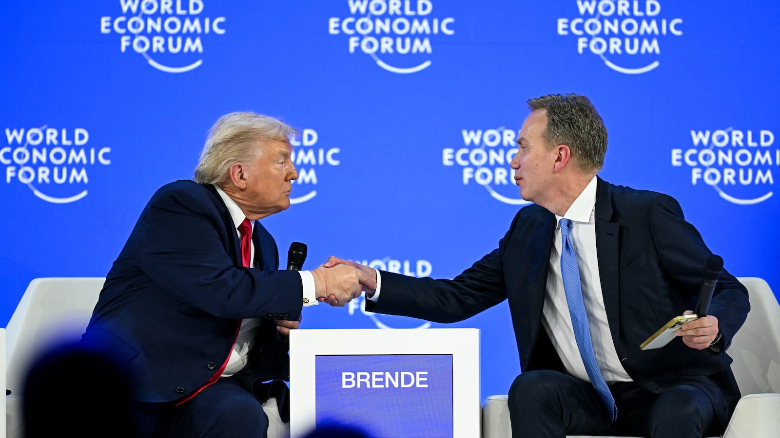 US President Donald Trump (L) shakes hands with World Economic Forum president and CEO Borge Brende during the World Economic Forum (WEF) annual meeting in Davos on January 21, 2026. The World Economic Forum takes place in Davos from January 19 to January 23, 2026. (Photo by Fabrice COFFRINI / AFP via Getty Images)