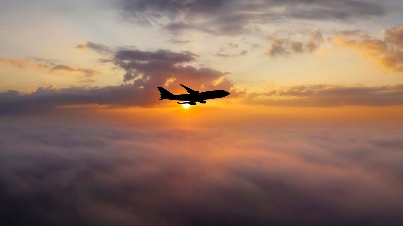 Airplane at sunset above the clouds.