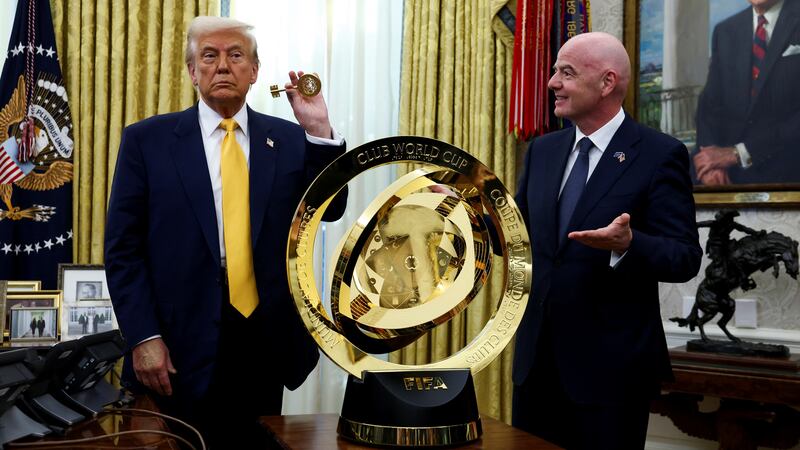 President Donald Trump and FIFA President Gianni Infantino stand next to the FIFA Club World Cup trophy in the Oval Office.