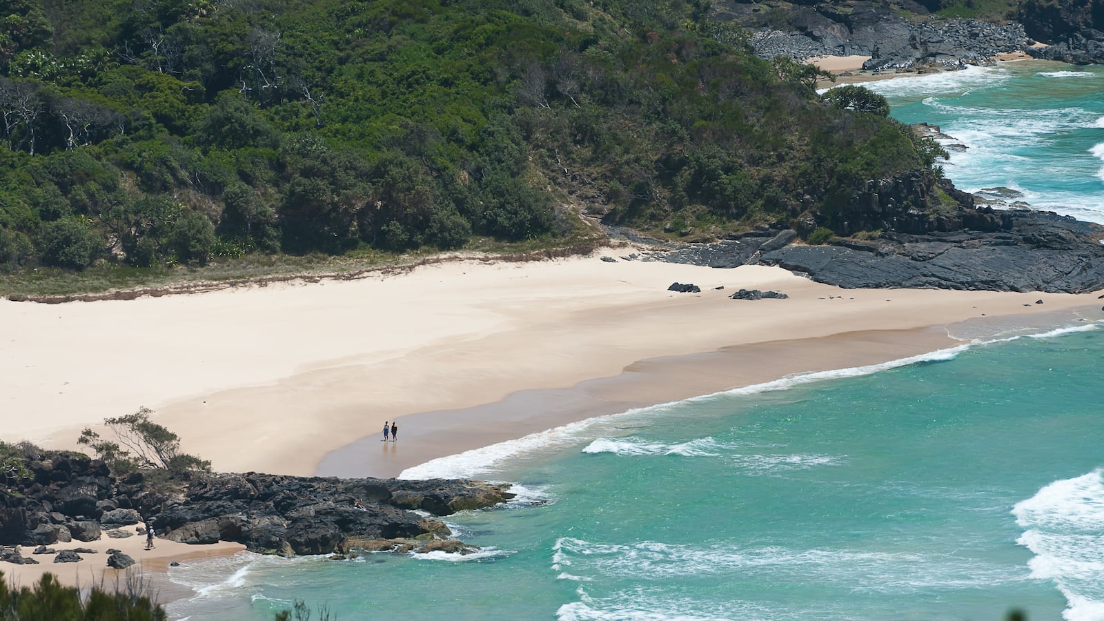 Clean sandy beach on the background of mountains and ocean waves
