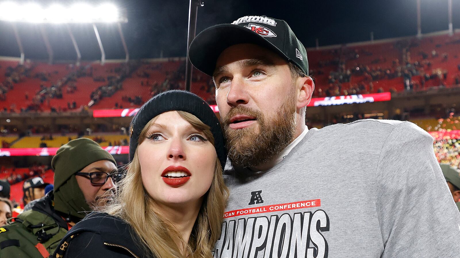 Taylor Swift and Travis Kelce standing together on a football field after the 2025 AFC championship gam.e