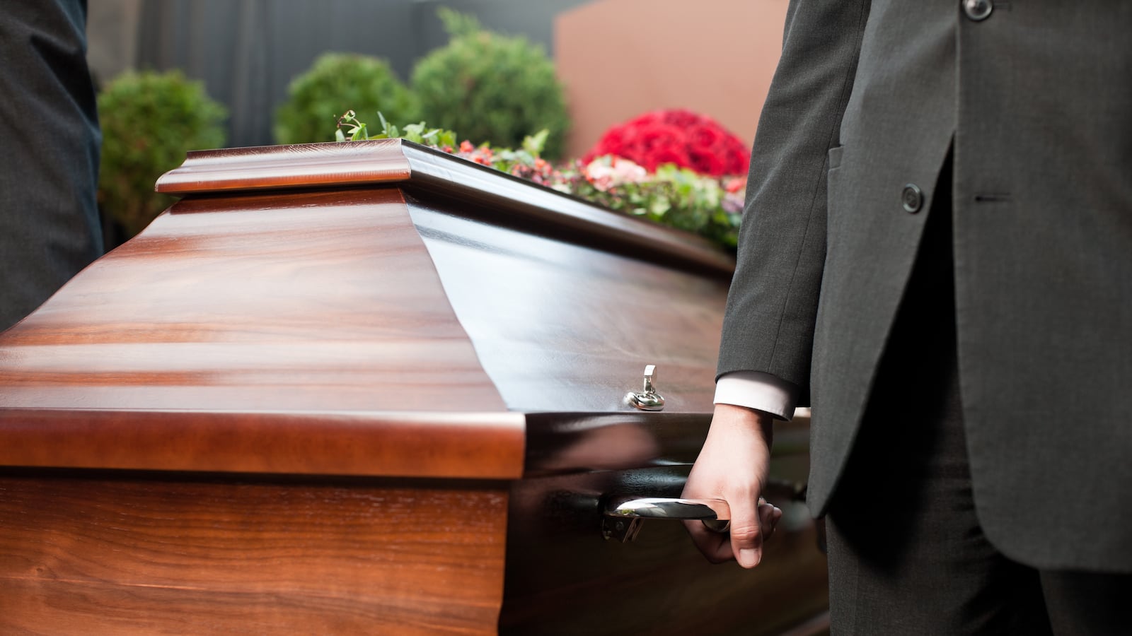 Funeral with coffin on a cemetery, the casket carried by coffin bearer