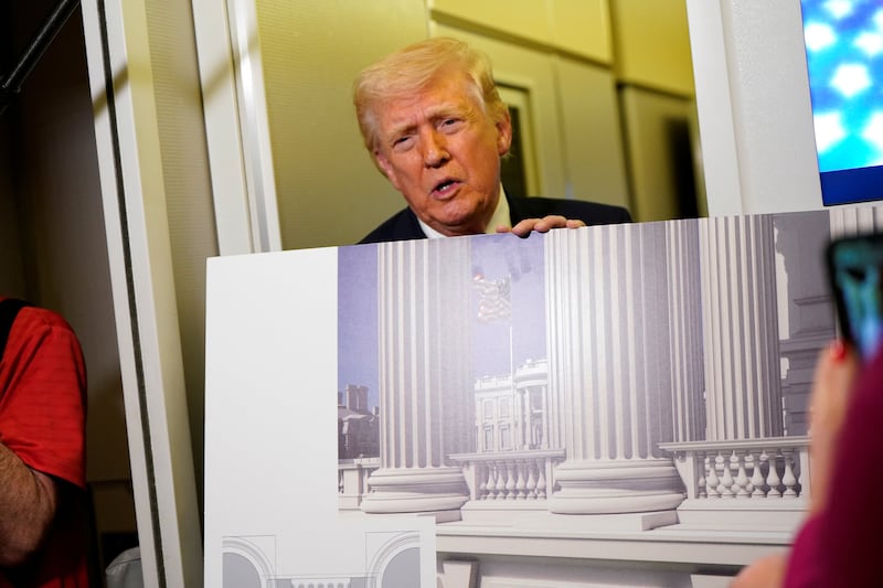 President Donald Trump talks to members of the media while holding up renderings of the planned White House ballroom, aboard Air Force One en route to Joint Base Andrews, Maryland, U.S., March 29, 2026.